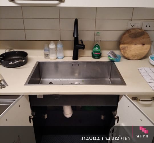 כיור מטבח עם ברז שחור וארון פתוח מתחת